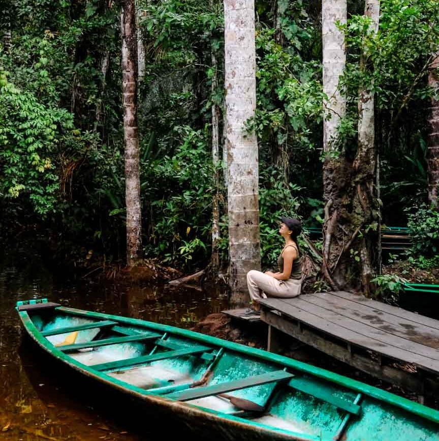 frau sitzt auf bootsanlegestelle im amazonas dschungel