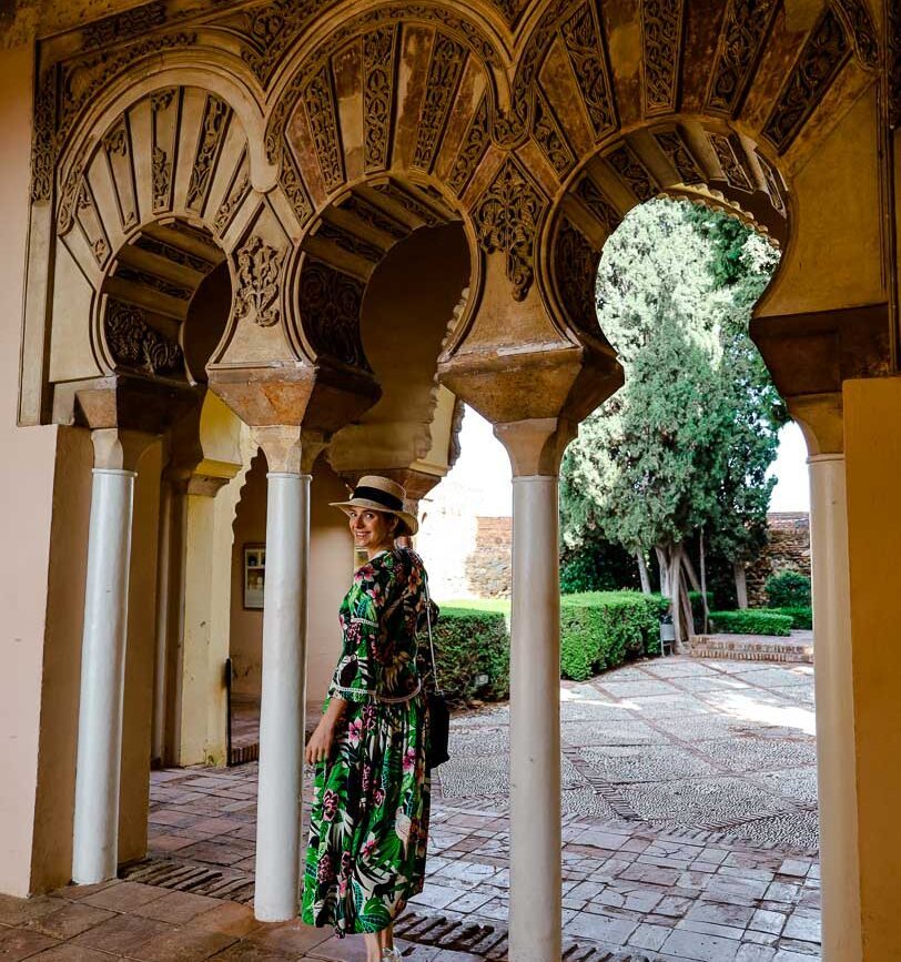 frau unter andalusischen boegen garten alcazaba im hintergrund