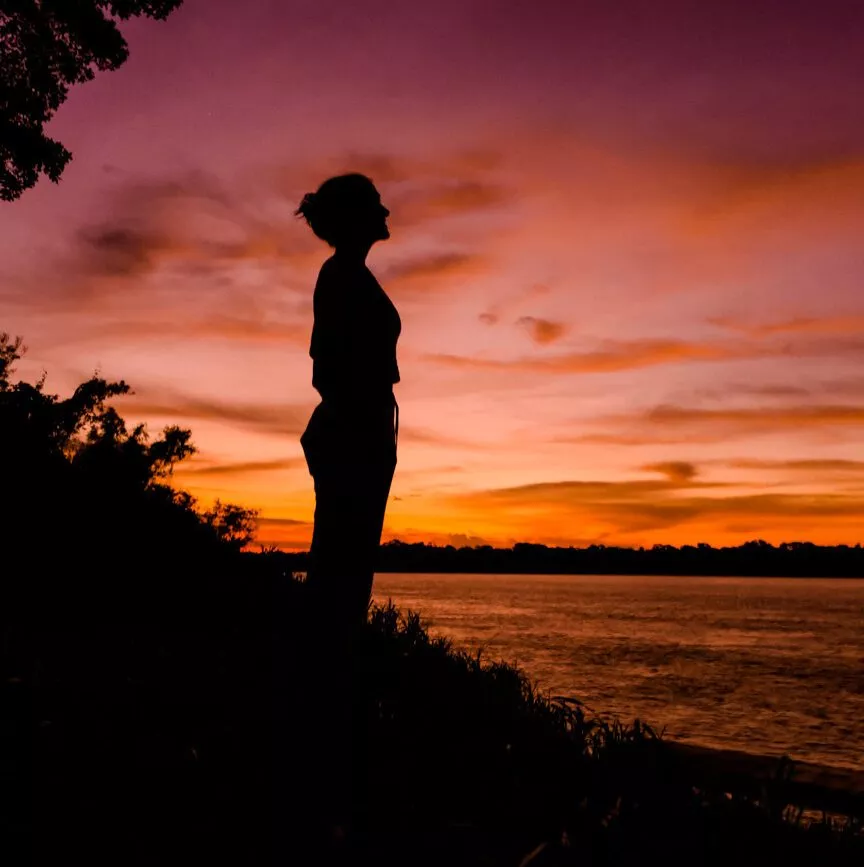 frauensilhouette am fluss bei sonnenuntergang in puerto maldonado