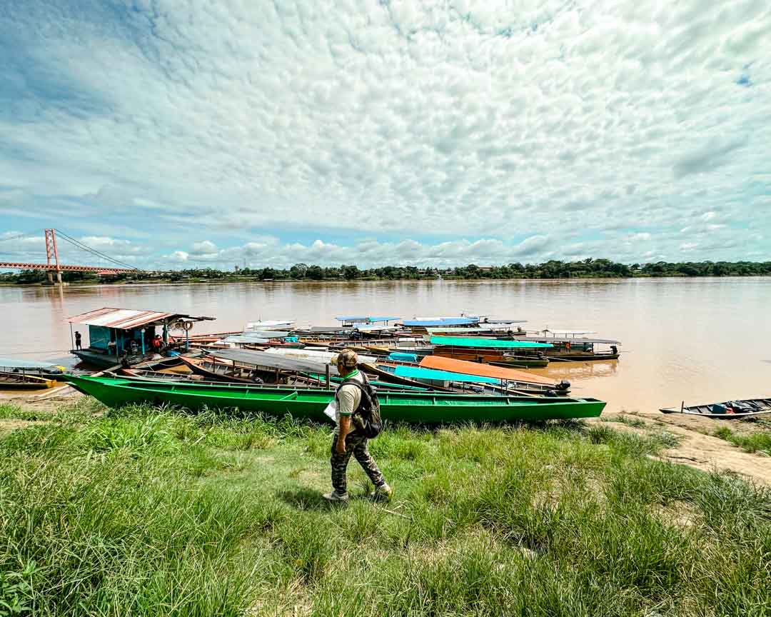 mann geht mit angedockten booten am amazonas entlang