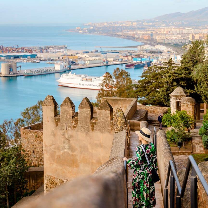 person steigt stufen auf gibralfaro in malaga hinab zu stadt und hafen in andalusien