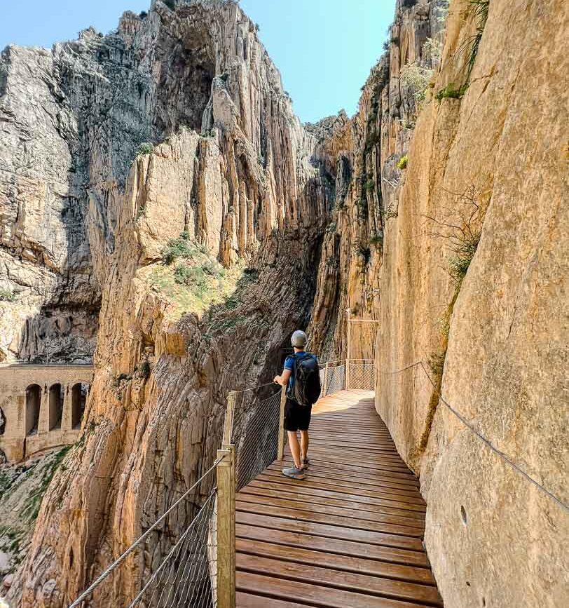 tom auf schmalem holzsteg an andalusischer steilkueste