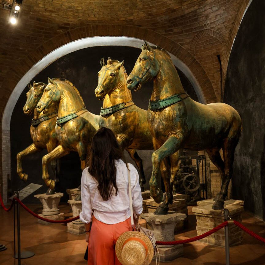 Frau betrachtet bronzene Pferde im Museum von Venedig