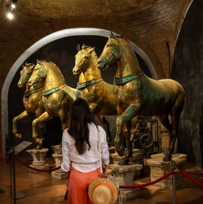 Frau betrachtet bronzene Pferde im Museum von Venedig