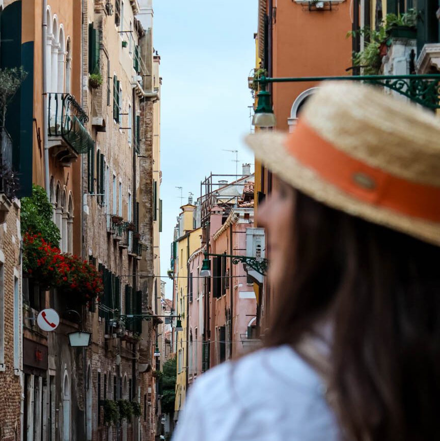 Frau im Strohhut sieht in engen Gassen Venedigs