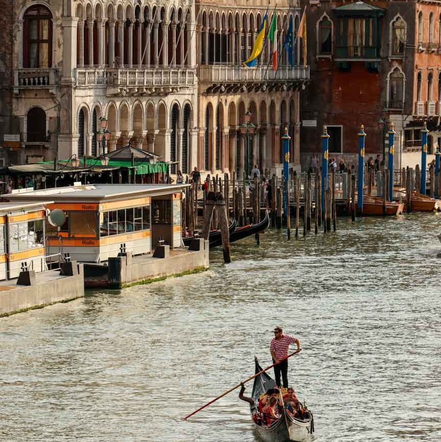 Gondoliere rudert mit Booten auf Kanal in Venedig