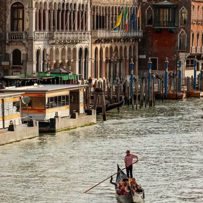 Gondoliere rudert mit Booten auf Kanal in Venedig