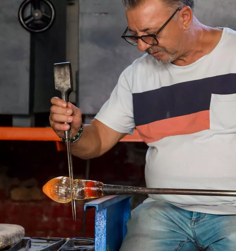 Mann formt heißes Glas in venezianischer Werkstatt in Murano