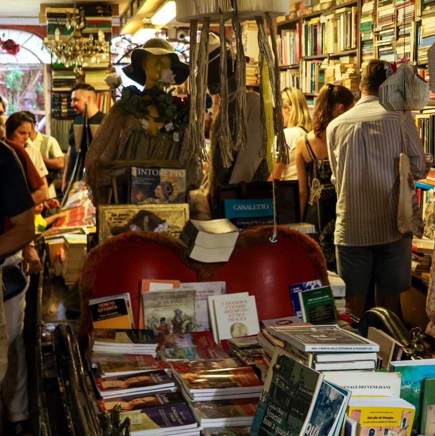 Menschen stöbern in Büchern in einem Buchladen in Venedig