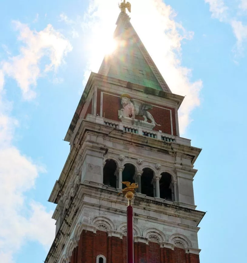 sonnenlicht flackert ueber dem markusturm in venedig