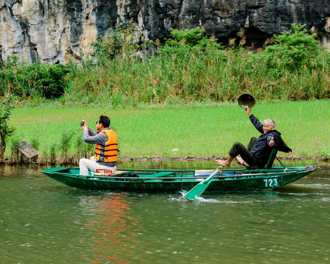 winkender vietnamese der mit fuessen paddelt in tam coc winkender vietnamese der mit fuessen paddelt in tam coc