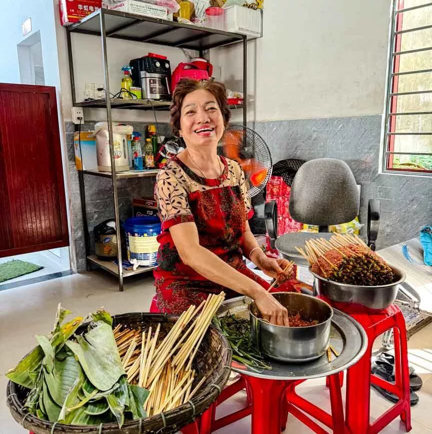 frau bereitet essen mit spiessen in hoi an zu