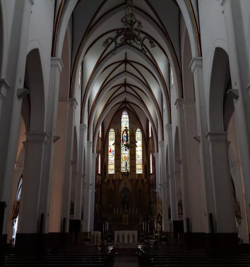Gotische Kathedrale in Hanoi, Vietnam mit hohen Bögen, Buntglasfenstern, Holzbänken und Altar
