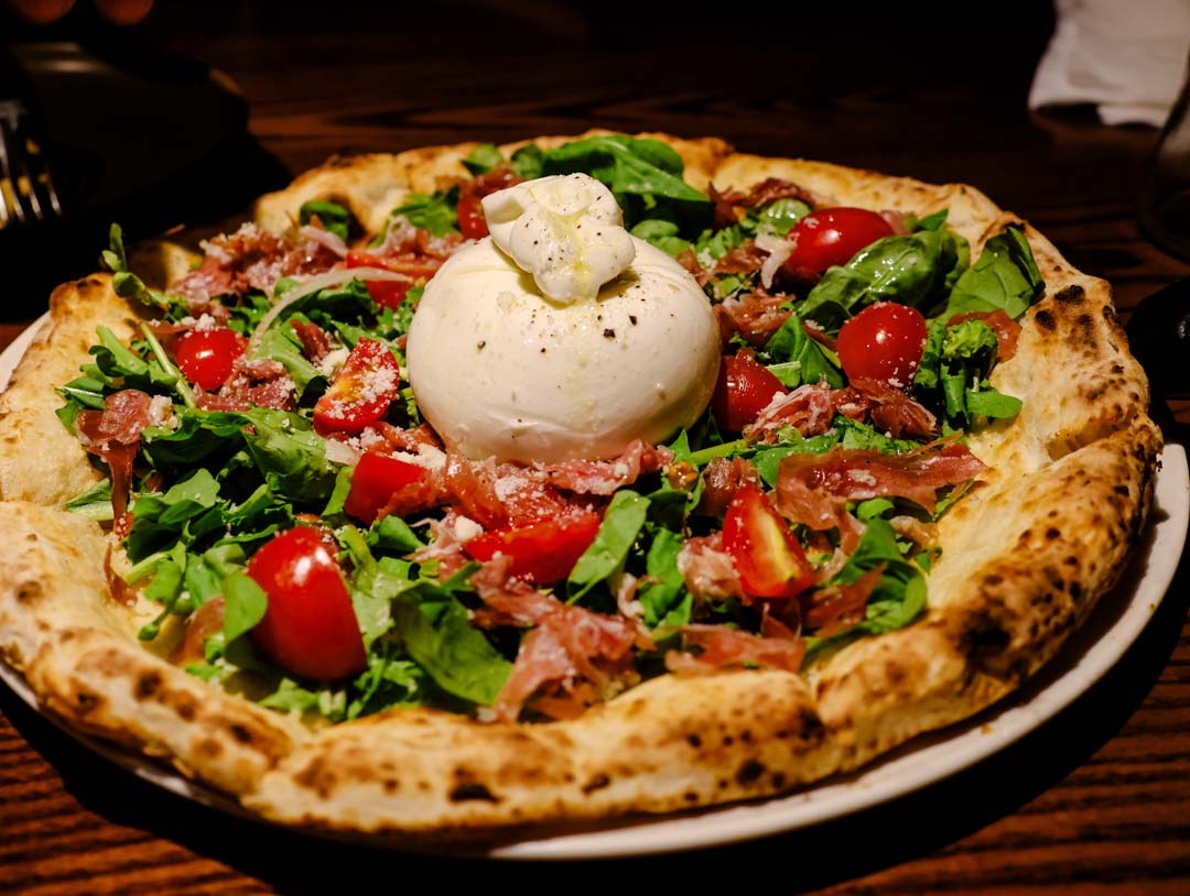 holzofenpizza mit rucola tomaten prosciutto burrata italienisch essen in hanoi vietnam