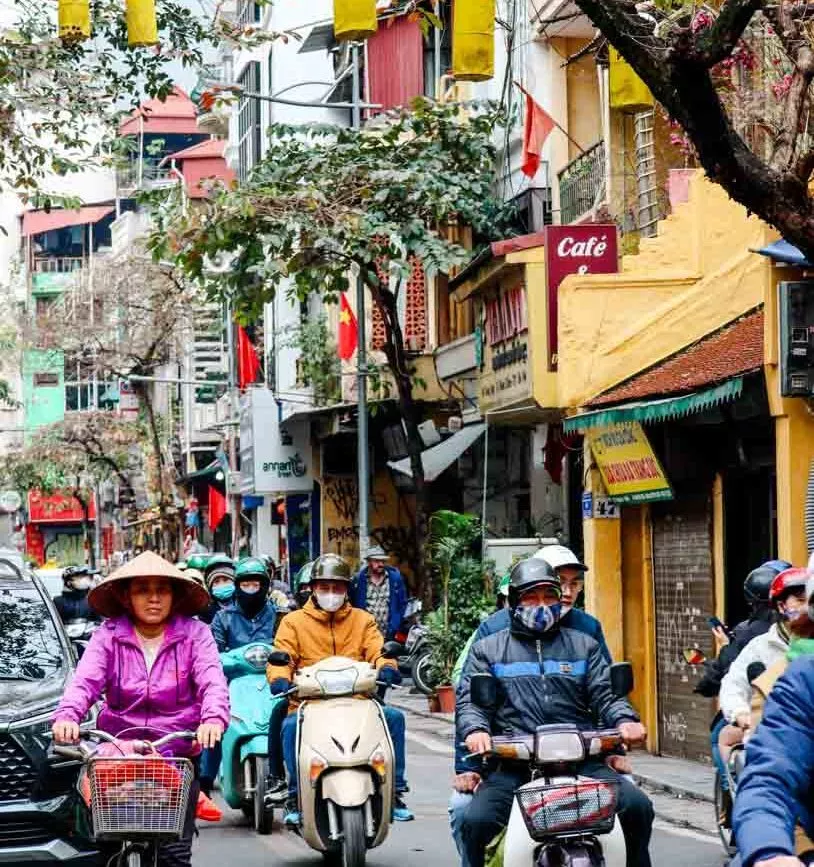 Straßenszene in Hanoi mit Motorrollern, Fahrrädern