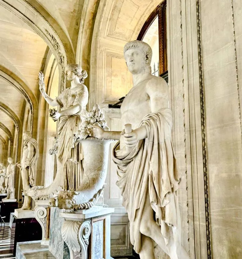 marmorstatuen in einem gewoelbten korridor im pariser museum