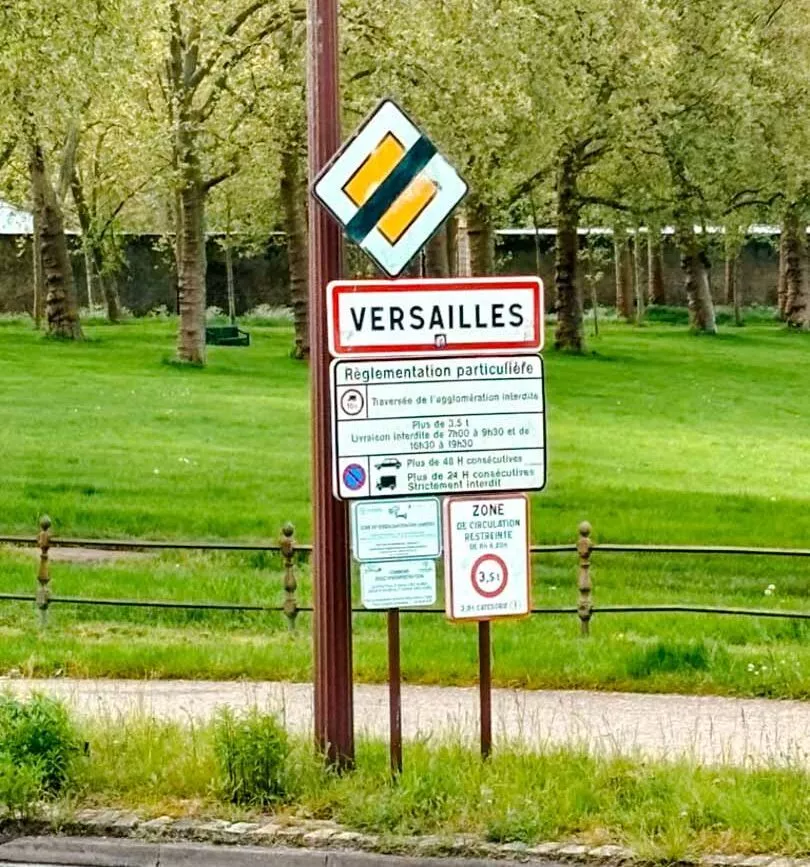 Ortschild mit der Aufschrift "Versailles" vor dem Schloss, Paris