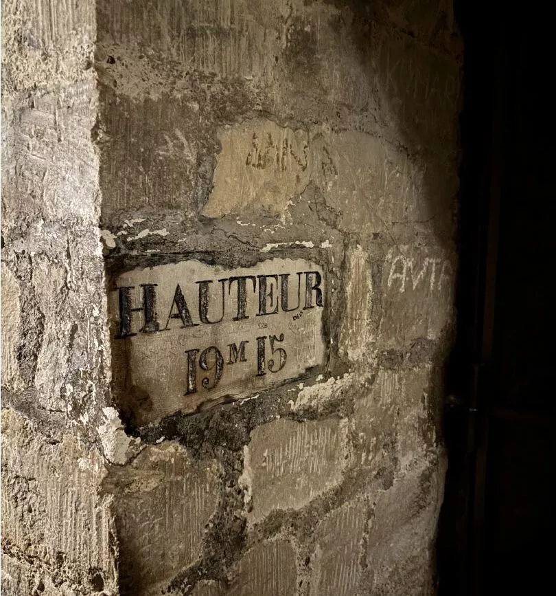 Unterirdisches Straßenschild "Hauteur 19m 15" in den Katakomben von Paris