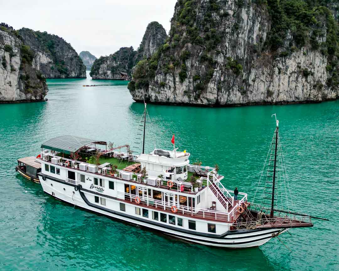 Boot segelt im türkisfarbenen Wasser, Halong Bucht Vietnam