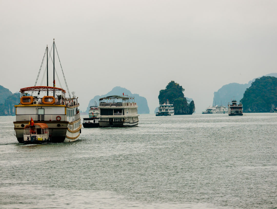 Boote auf dem Weg in die Halong Bucht, neblige Inseln sichtbar