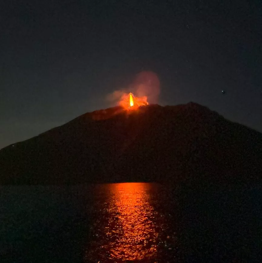 Der Vulkan Stromboli bricht nachts aus und die Lava spiegelt sich im Wasser