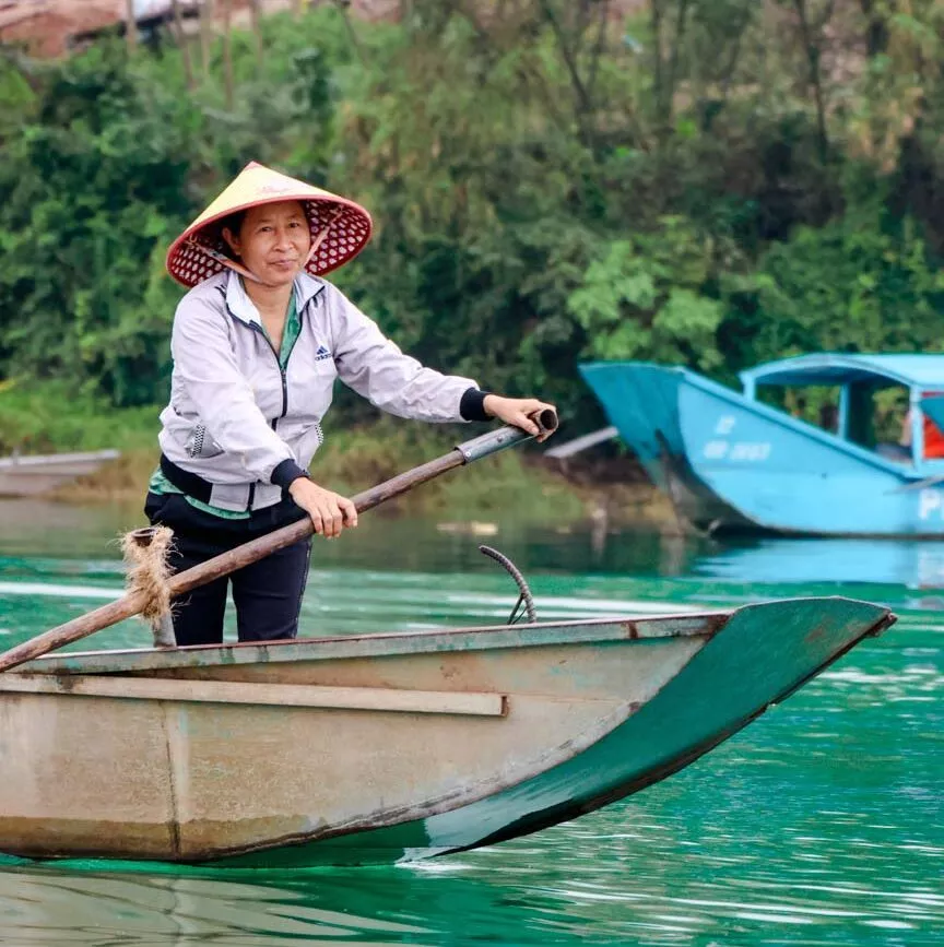 person mit kegelhut in boot auf phong nha