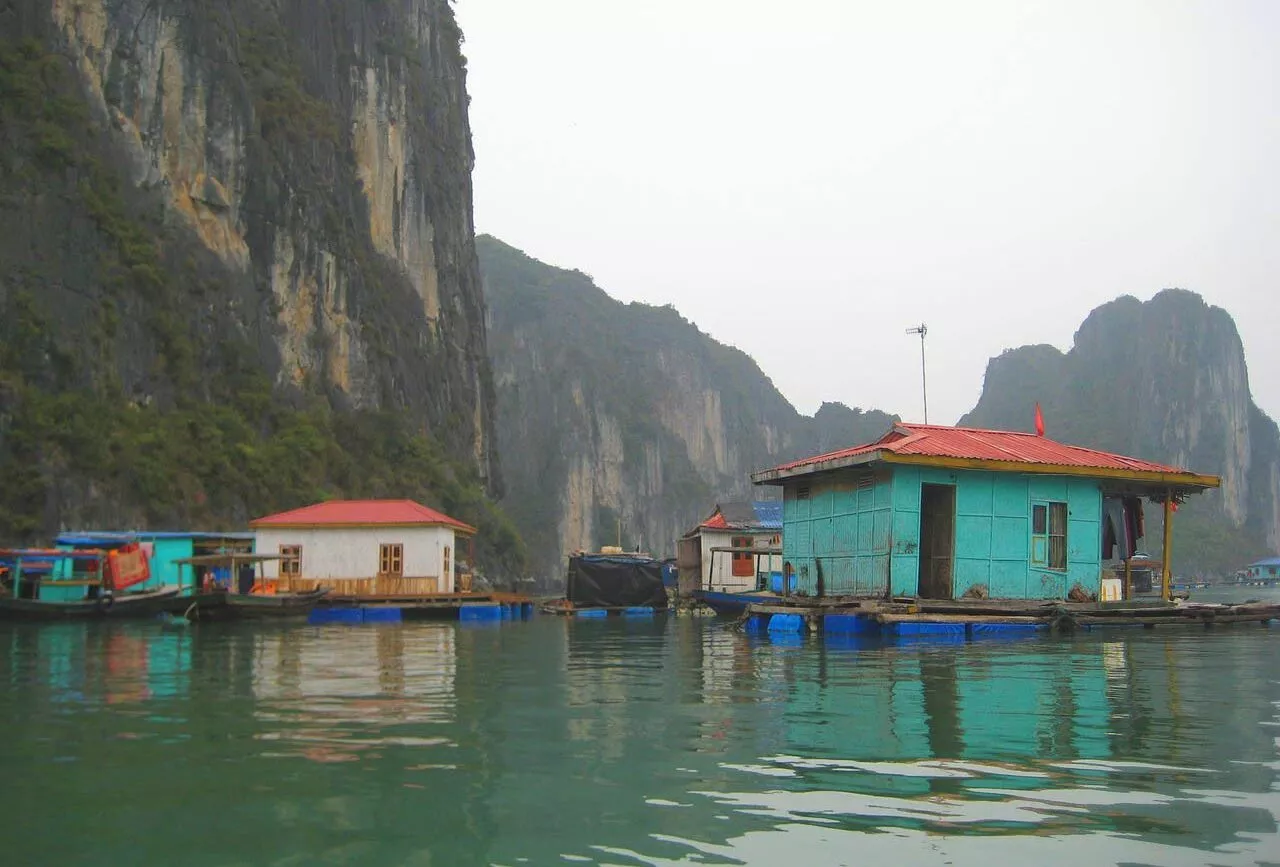 Schwimmende Häuser auf dem Wasser mit Klippen in der Halong Bucht