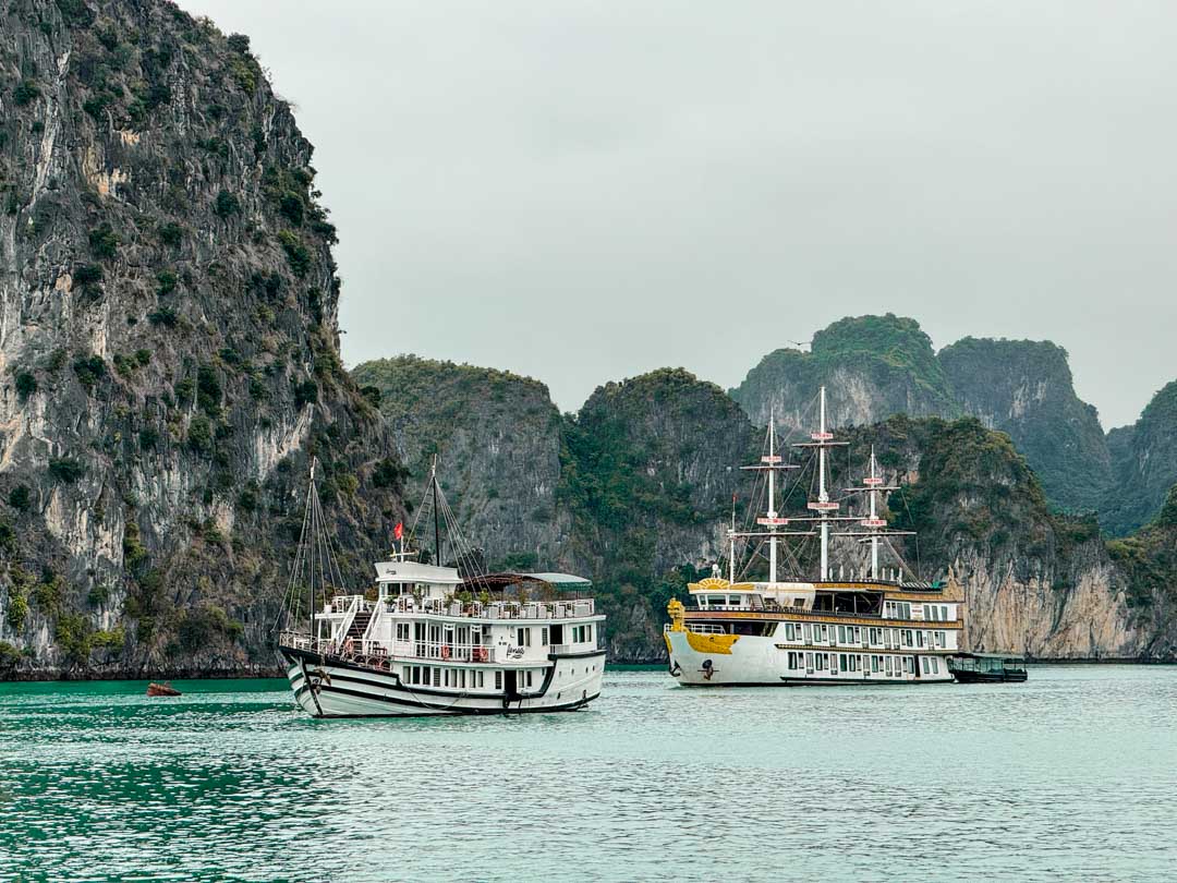 Zwei unterschiedlich große Boote in der Halong Bucht, felsige Klippen