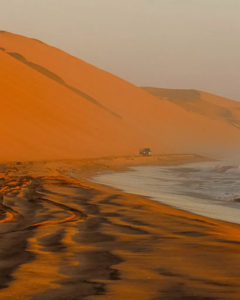 gelaendewagen faehrt zwischen duene und atlantik bei sandwich harbour tour Geländewagen fährt zwischen Düne und Atlantik Sandwich Harbour Tour